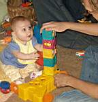 20050205 06c - Emily (6 mo) getting ready to pull down Daddy (Matt)'s stack of blocks.jpg