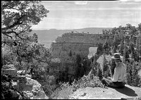 NPS RANGER SITTING ON NORTH RIM LOOKING OUT AT ANGELS WINDOW. CAPE ROYAL. JULY 1932. NPS PHOTO.