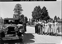 NORTH RIM LODGE EMPLOYEES STANDING BY A UNION PACIFIC TOURING CAR, SINGING FAREWELL TO GUESTS WITH THE RUINS OF THE GRAND CANYON LODGE BEHIND THEM. (THE SUMMER AFTER THE FIRE) JUNE 1933 NPS PHOTO<br>