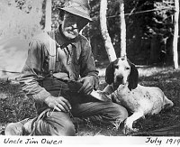 UNCLE JIM OWENS BANDAGING THE FOOT OF A HIS LION HUNTING HOUNDS IN A NORTH RIM MEADOW. JULY 1919. CLAFLIN, WILLIAM. 