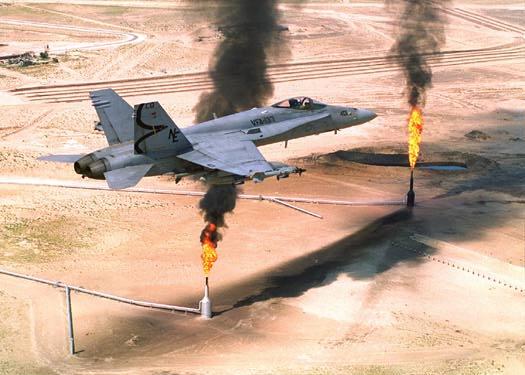 An American F/A-18 flies over a burning oil well in Saudi Arabia
