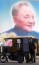 A motor carriage driver waits near his vehicle before a billboard of former Chinese leader Deng Xiaoping in Golmud city, Qinghai province in western China on Friday, July 20, 2001. China is seeking to develop its western region, home to many of its ethnic and religious minorities, some of whom have traditionally resented heavy-handed Chinese rule. (AP Photo/Ng Han Guan)