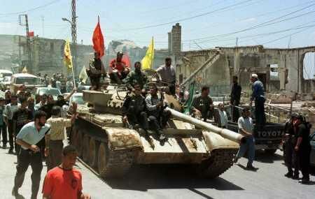Hizballah fighters drive an abandoned SLA tank through the streets.