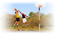 Image of two young men playing basketball.  One blocks as the other shoots a jump shot