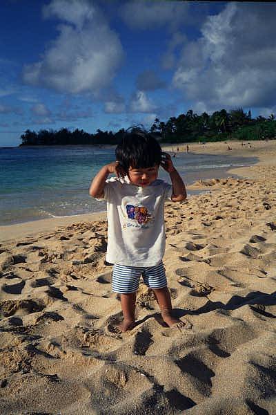 Yuto touching his ears at the beach.