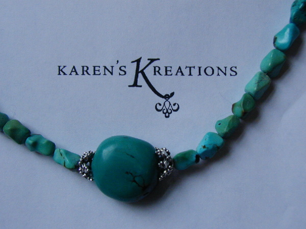 A detail of a turquoise and silver neckless in front of our brand new logo
