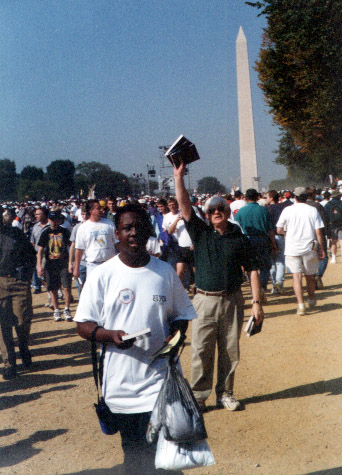 A man, standing below the Washington Monument, waving a Bible.