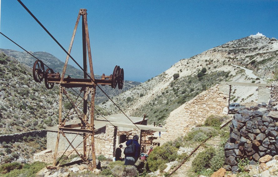 Κοιτάσματα σμύριδας υπάρχουν σε όλη την μαρμάρινη ραχοκοκαλιά της οροσειράς που διατρέχει από Β προς Ν τη Νάξο με μεγαλύτερη συγκέντρωση στην Αμμόμαξη, βουνό τρύπιο από τις στοές σα σφουγγάρι. Στην αρχαιότητα με την σκληρή σμύριδα λάξευαν τα αινιγματικά προϊστορικά βραχογραφήματα, τα κυκλαδικά μαρμάρινα ειδώλια και τα αρχαϊκά αγάλματα. Μεταξύ 1923-24 κατασκευάστηκε ο μήκους 8 χλμ. εναέριος σιδηρόδρομος με τους 71 επιβλητικούς πυλώνες (3-50μ. ύψος) που μαζί με τους 5 σταθμούς φόρτωσης ήταν ίσως το μεγαλύτερο βιομηχανικό έργο της εποχής στα Βαλκάνια, που κόστισε 40.000 λίρες, και έδωσε προπολεμικά άνθηση στα 6 ορεινά σμυριδοχώρια. Λειτούργησε από το 1928 ως το 1978 και σήμερα, οτι δεν έχει ξεπουληθεί για παλιοσίδερα, από τον κατά τα άλλα κηρυγμένο αρχαιολογικό χώρο, έχει ενταχθεί για αποκατάσταση και αξιοποίηση. Τους γιγάντιους πυλώνες σύντομα θα ανταγωνίζονται 8 ανεμογεννήτριες που θα υψωθούν σε ανεμολογικά επιλεγμένη έκταση 600στρμ. της Αμμόμαξης, στο πλαίσιο του έργου Αιολικό Πάρκο Νάξου, ύψους 3.5δις δρχ. που εγκρίθηκε πρόσφατα.