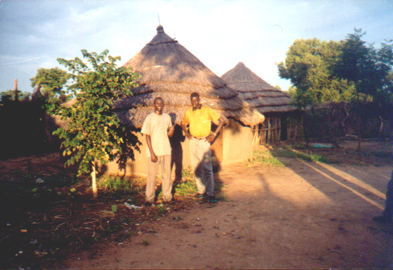 St. Luke's members standing in front of buildings made from local materials