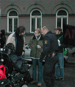 Tv icke-funktionshindrade aktivister och en funktionshindrad aktivist i permobil talar med en polis.