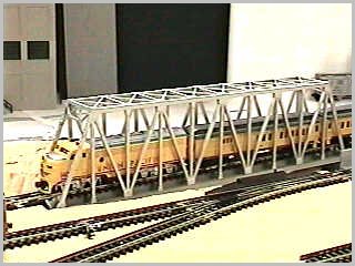 Passenger train through truss bridge - side