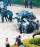 Police take cover beside an overturned car protecting themselves with shields against a shower of bricks at the height of the attack. [Shenzhen Daily]
