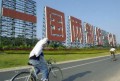 Locals ride bicycles past a big sign of government's anti-Taiwan propaganda saying in Chinese, "One country Two systems Unite China" Saturday, Dec. 30, 2000 in Xiamen, China, only several miles away from Taiwan-controlled islands.- Photo by Eugene Hoshiko (AP) 