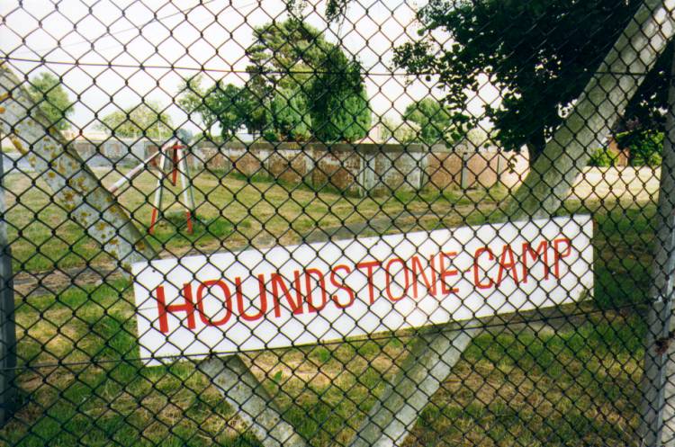 (c.1996) Houndstone Camp sign which is very temporary looking, the foundations of the Guard House behind, and manual lift barrier which appears to be too far away from the road to have been any use. perhaps indicates wider entrance gate before re-fencing took place