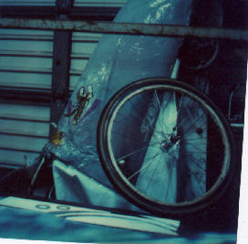 Image of a past bike with front wheel off and the start of a wheel cover with balsa wood strips on the rim to be used for covering with model airplane covering