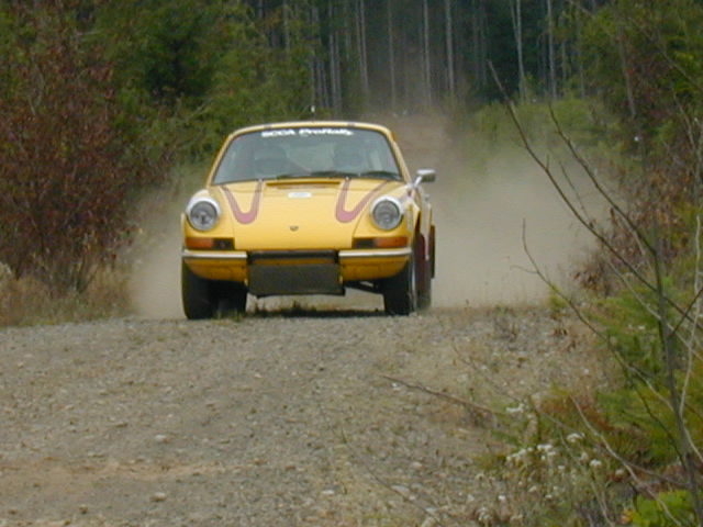 Picture of Rally Car traveling at you on a logging road in the woods.