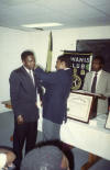 DP Dennis Robotham affixes a pin to the lapel of DP Wilford