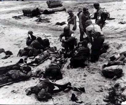 Medics help a wounded soldier on blood- stained Omaha Beach on June 6th 1944