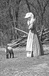 A farmer from 1850 style simulated park with a newborn lamb.