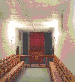  Chairs line the wall, and a simple altar lies at one end, and a doorway behind tha.  In an adjacent room near the viewer in this photo, is a kitchen.