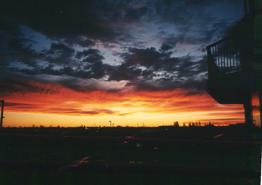 Photo Copyright Milson Macleod 1999. Sunset from Edmonton, Alberta, looking towards the Rocky Mountains and the abode of Archangel Michael. Atypical buildings are visible among the clouds - not a reflection of local architecture!