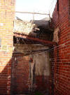 Bizarre brickwork and masonry with hanging barbed wire hangs precariously off this building