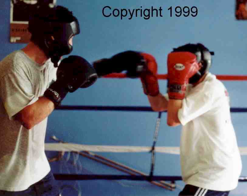 Boxer on the right blocks lead punch and keeps his guard up in anticipation of the right from a taller opponent with a longer reach.  Image copyright 1999.  All rights reserved.