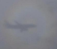 Picture of shadow of airplane surrounded by rainbow