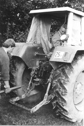Rudi koppelt routiniert mit Zigarette im Mund an Jans Traktor an (SW)