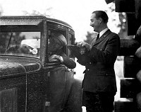 RANGER PERRY E. BROWN CHECKING IN CAR (OLD) AT SOUTH ENTRANCE STATION. JUNE 1931. NPS PHOTO BY COLLINS.  