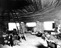 INTERIOR DESERT VIEW WATCHTOWER KIVA ROOM. MARY COLTER DECOR. NATIVE EMPLOYEE BY FIREPLACE.TIMBERS SALVAGED FROM GRANDVIEW HOTEL. GRCA 15934 CIRCA 1932. FRED HARVEY CO.