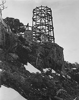LOOKING UP AT WATCHTOWER & KIVA UNDER CONSTRUCTION FROM BELOW DESERT VIEW POINT. CIRCA 1932. FRED HARVEY CO. GRCA 22651