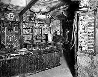 JACK TIMECHE, HOPI CLERK, BEHIND RETAIL COUNTER IN DESERT VIEW WATCHTOWER SHOP. GRCA 15938. CIRCA 1932. FRED HARVEY CO. 