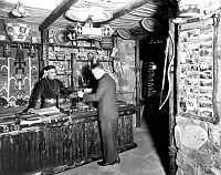 JACK TIMECHE, HOPI CLERK, BEHIND RETAIL COUNTER IN DESERT VIEW WATCHTOWER SHOP. CIRCA 1932. FRED HARVEY CO. 