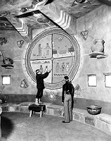 HOPI ARTIST FRED KABOTIE EXPLAINING THE SNAKE LEGEND PAINTING IN THE DESERT VIEW WATCHTOWER.GRCA 22671B. CIRCA 1932. FRED HARVEY CO. 
