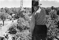 WORKER STANDING IN OPEN WATCHTOWER FRAMEWORK AS LARGE BOULDER IS BEING HOISTED UP TO HIM. CIRCA 1932. COLTER. 
