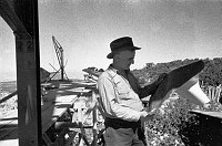 MAN STANDING IN WATCHTOWER CONSTRUCTION SITE HOLDING PLANS. CIRCA 1932. COLTER.