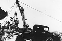 WORKERS USING WINCH TO POSITION ROCKS ON TRUCK BED. DESERT VIEW WATCHTOWER. CIRCA 1932, HIRCHBORN