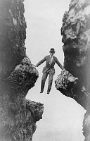 T.L. BROWN, FORMER TRAIL GUIDE, SUSPENDED BETWEEN 2 VERTICAL LIMESTONE WALLS. CIRCA 1915. BROWN. 