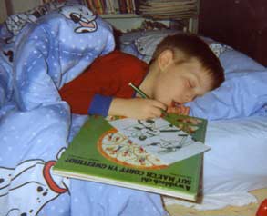 boy in bed asleep still holding felt pen on paper with drawing of ancient soldiers