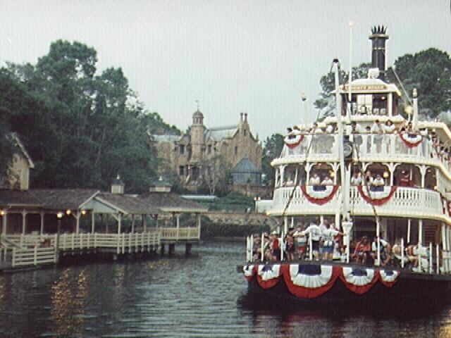 The Liberty Belle Riverboat with Tom Sawyer's Island and the Haunted Mansion in the background