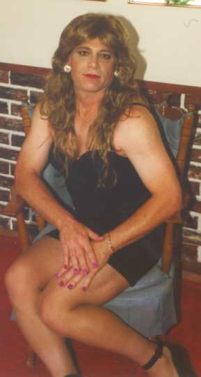 Cynamin in black miniskirt sitting in chair facing us