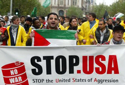 Stop the United States of Aggression. 10 November 2002: A protester holds a Palestinian flag behind a banner criticising US foreign policy in the Middle East during an anti-war march in Brussels.